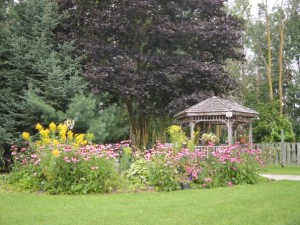 Walkway to a Gazebo surrounded by trees and flower beds