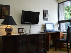 Indoor office area with television mounted on wall, and a computer desk 