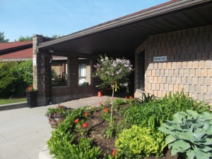Outside front entrance of single storey building with flower beds and shrubbery 