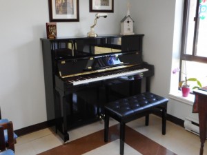 Piano in the corner of a room with a large window  